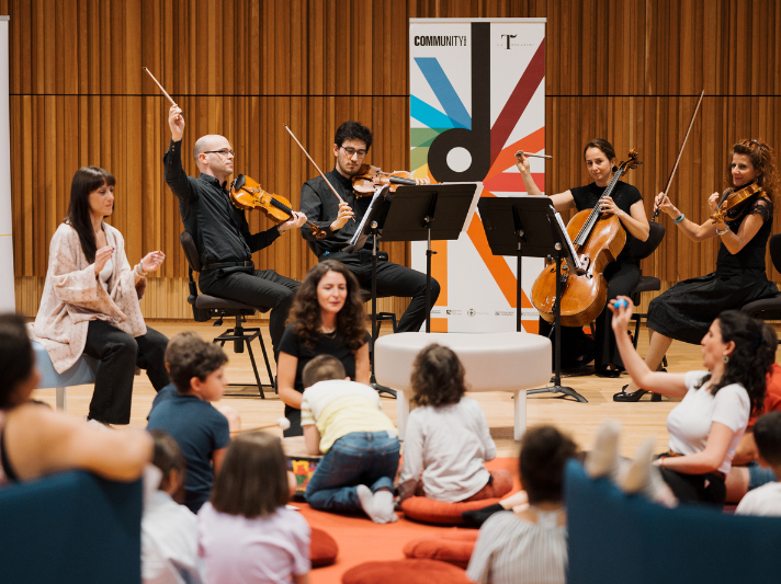 Un cerchio di bambini e genitori durante un laboratorio musicale interattivo